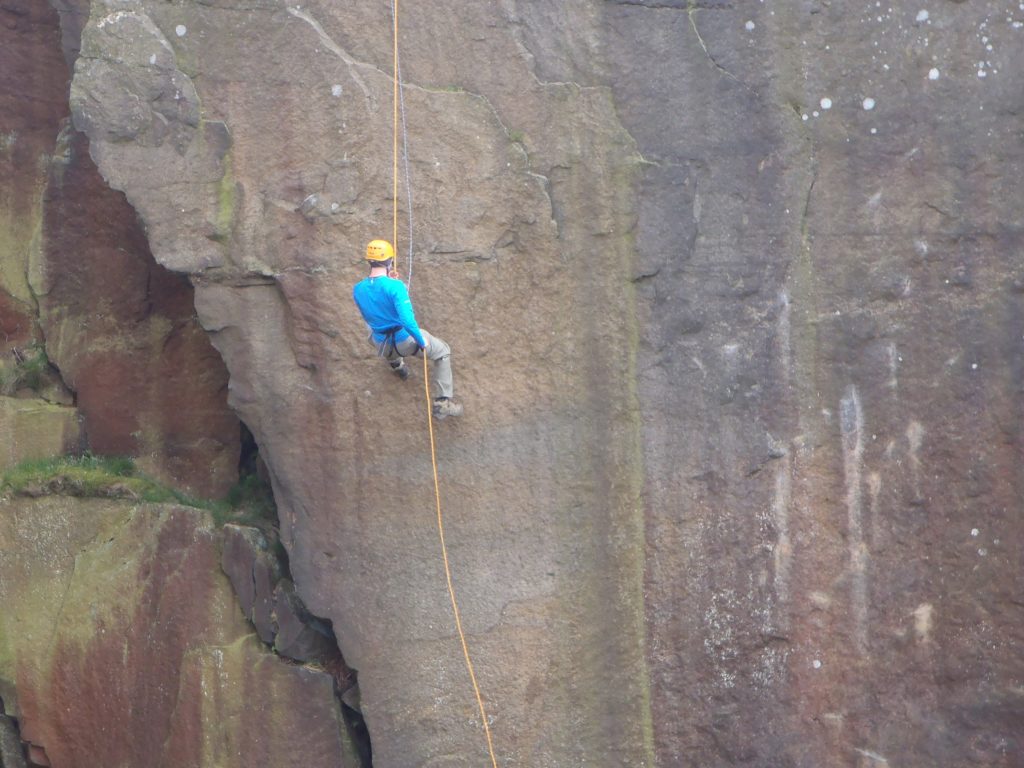 A person abseiling down a steep quarry