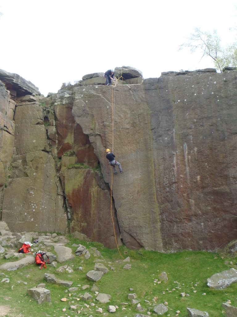 A person abseiling down a steep quarry